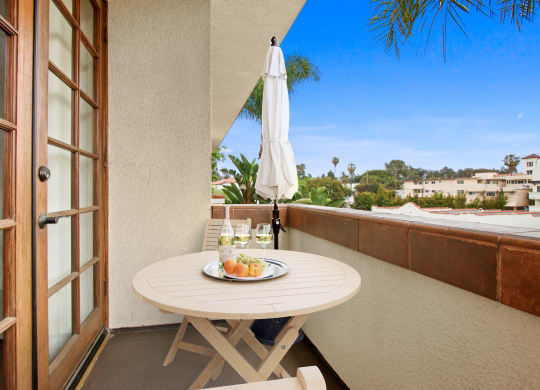 a balcony with a table and an umbrella on a balcony at Darlington Apartments, Los Angeles, CA