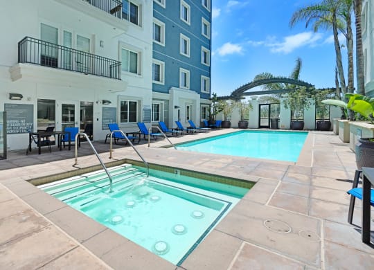 a swimming pool with blue chairs and a blue building in the background  at Apex Mission Valley, San Diego, California