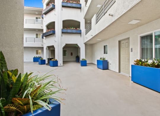 a large white building with blue planters on the outside at Alon Apartments, Los Angeles