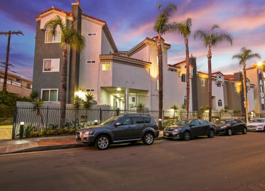 a row of apartment buildings with palm trees in front of them at Alon Apartments, Los Angeles