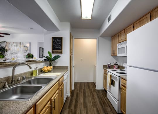 a kitchen with white appliances and wooden cabinets at Bella Terra Apartments, Henderson, 89012