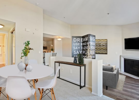 a dining area with a white table and chairs and a fireplace in the background at Palm Royale Apartments, California, 90034