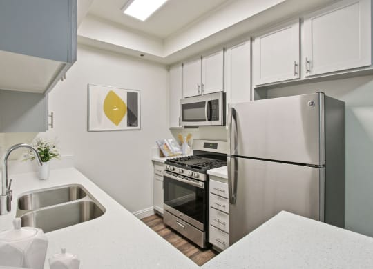 a kitchen with white cabinetry and stainless steel appliances at Palm Royale Apartments, California, 90034