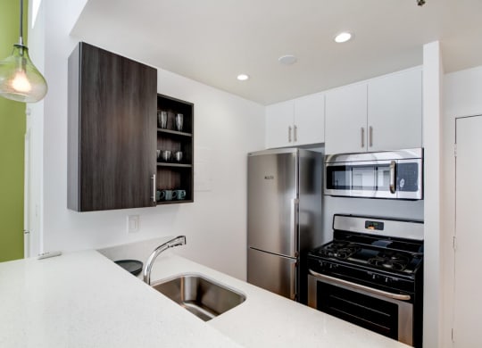 a kitchen with white cabinets and green walls  at El Greco Lofts, Los Angeles, 90024