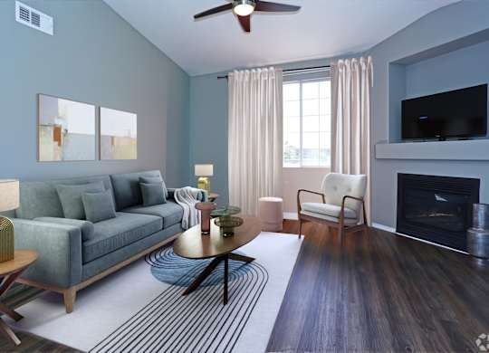 A living room with a grey couch, a fireplace, and a ceiling fan.