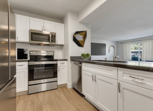 an open kitchen with stainless steel appliances and white cabinets at Bella Terra Apartments, Henderson, 89012