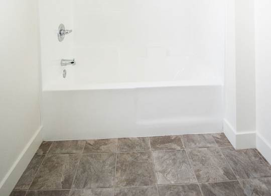 A white bathroom with a tiled floor and a shower.