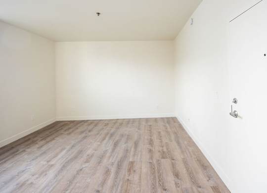 A room with wooden flooring and white walls.