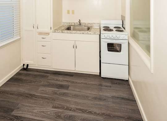 A kitchen with white cabinets and a vinyl floor.