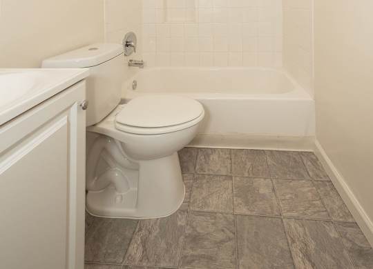 A white toilet sits in a bathroom next to a bathtub.