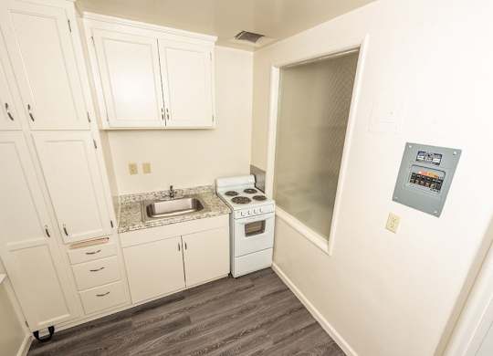 A small kitchen with white cabinets and a stove top oven.