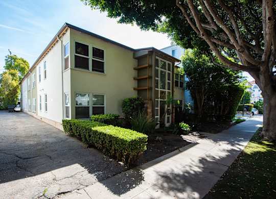 A two-story building with a green hedge in front.