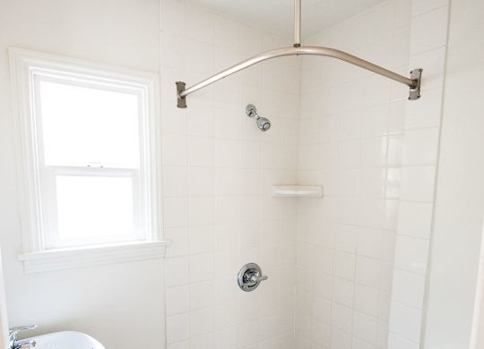 A white bathroom with a toilet, sink, and shower.