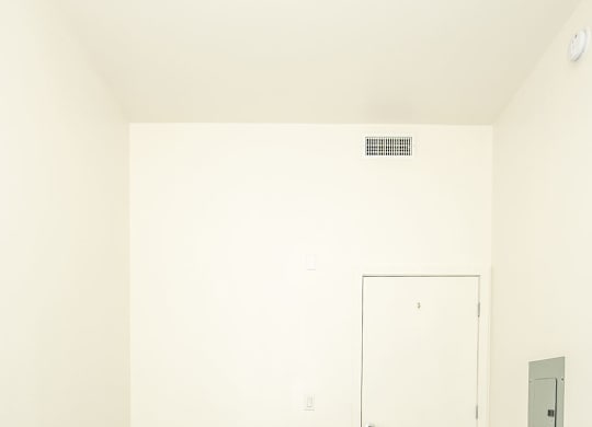 A room with a white door and a light switch on the wall.
