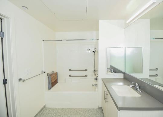 A white bathroom with a sink, mirror, and shower.