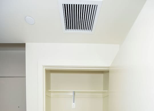 A white closet with a white door and a white shelf.