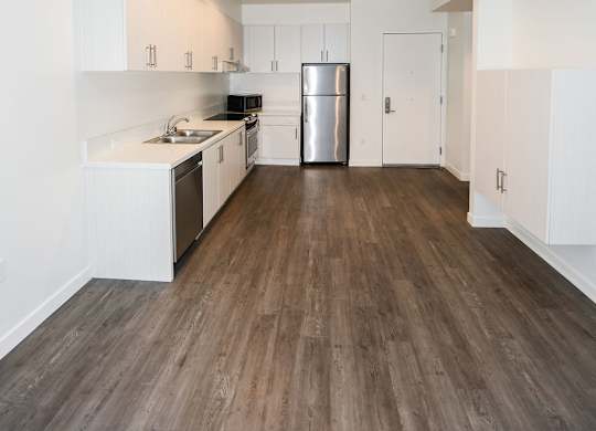 A kitchen with white cabinets and a wooden floor.