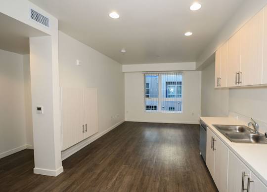 A kitchen with white cabinets and a window.