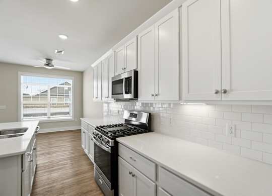 A kitchen with white cabinets and a black stove top.