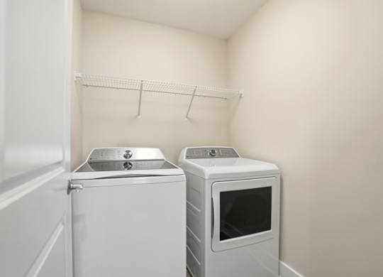 A white washing machine and microwave in a small laundry room.