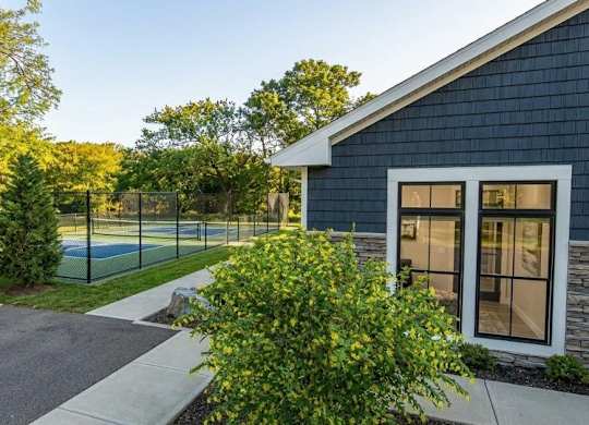 A blue house with a tennis court in front.