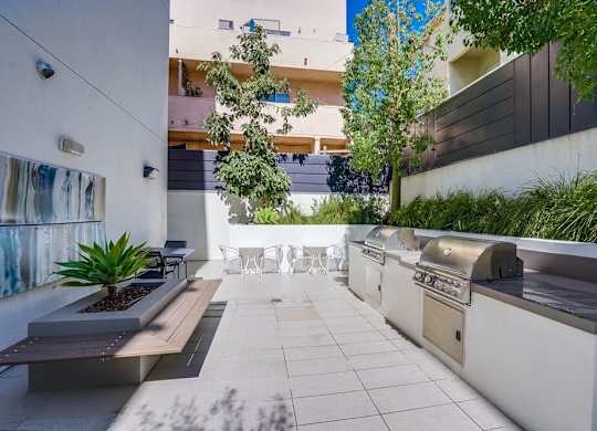 A modern outdoor patio with a bench, table, and plants.at Vues on Gordon, Los Angeles California