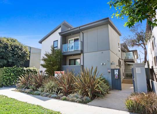an apartment building with a sidewalk and plants in front of it at The Aster, California