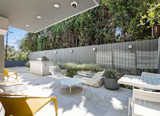a patio with a table and chairs and a privacy fence at The Aster, Los Angeles, 90024
