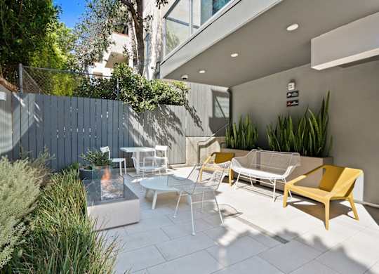 a patio with chairs and tables and a blue fence at The Aster, Los Angeles