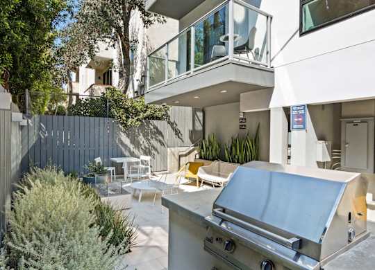 a backyard with a barbecue grill and a patio with tables and chairs at The Aster, Los Angeles