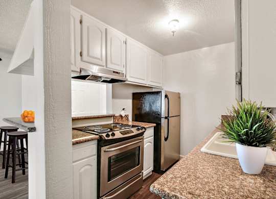 Kitchen with Stainless steel appliances including electric range over range hood, two door refrigerator, white kitchen cabinets, granite countertops
