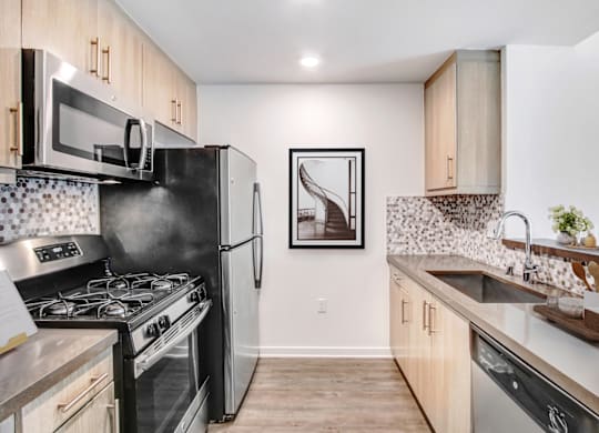 A kitchen with a black refrigerator, stove, and microwave.at Vues on Gordon, Los Angeles 
