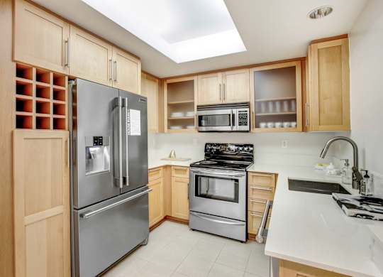 A kitchen with a refrigerator, oven, microwave, and sink.at Wilshire Margot, Los Angeles, CA 90024 