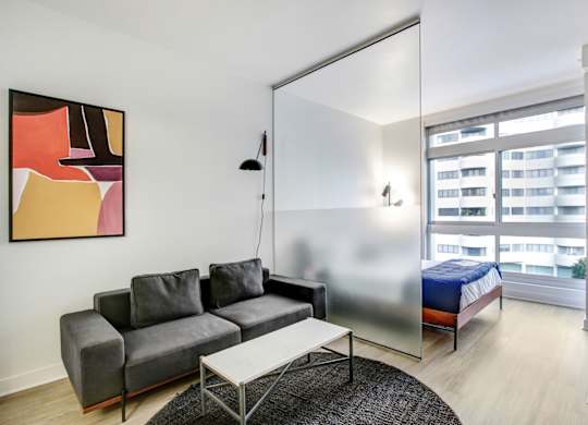 A living room with a grey couch and a painting on the wall.at Wilshire Margot, California, 90024