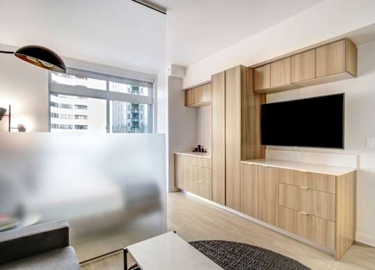 A modern living room with a television and a black floor lamp.at Wilshire Margot, Los Angeles, CA 