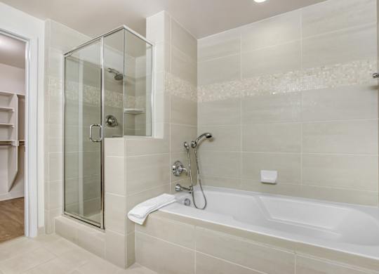 A modern bathroom with a glass shower enclosure and a white bathtub.at Wilshire Margot, Los Angeles, 90024 