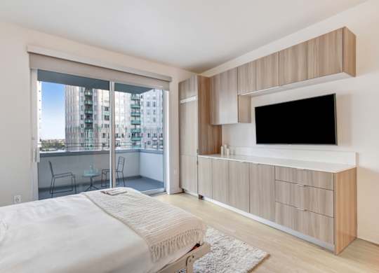 A bedroom with a large bed and a television on the wall.at Wilshire Margot, California, 90024