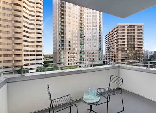 A balcony with a table and two chairs overlooks a cityscape.at Wilshire Margot, Los Angeles California 