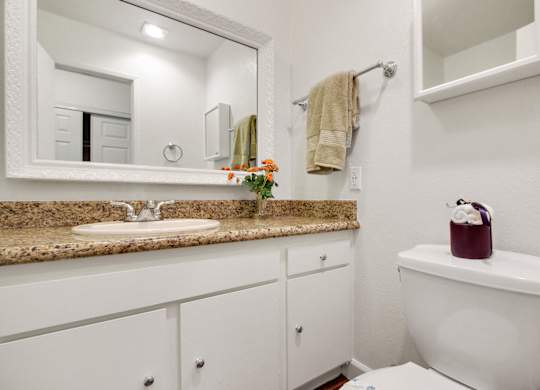 Bathroom with single vanity, granite countertops, white cabinets