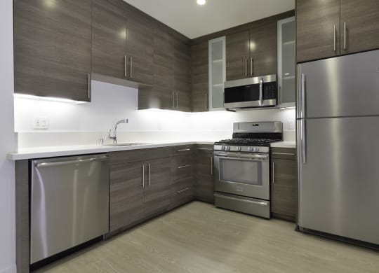a kitchen with stainless steel appliances and wooden cabinets at Seventh West Apartments, Santa Monica 
