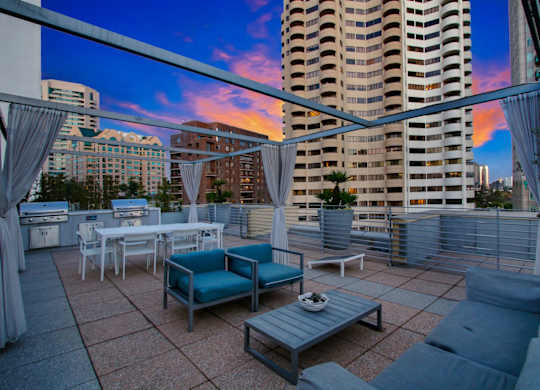 A rooftop patio with a table set for dining and a view of the city.at Wilshire Margot, California, 90024