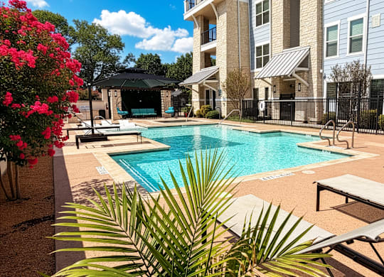 A pool surrounded by lounge chairs and a fence.