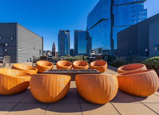 a lounge area with orange chairs and a table in front of tall buildings