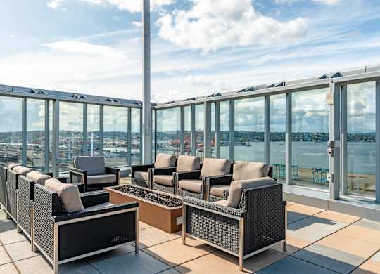 a seating area with wicker chairs and a view of a river and a city