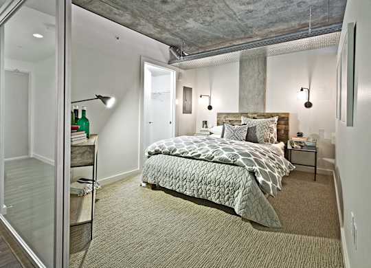 a bedroom with a bed and a concrete ceiling