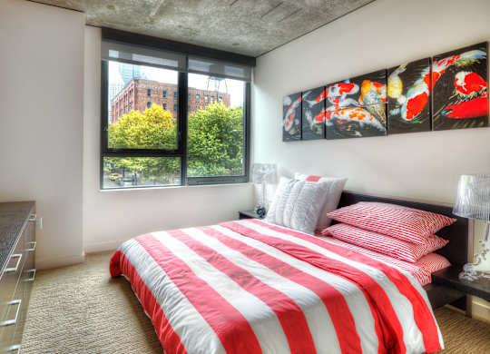 a bedroom with a red and white bed and a window