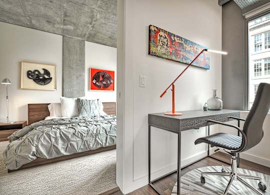 a bedroom with a bed and a desk with a chair and a lamp