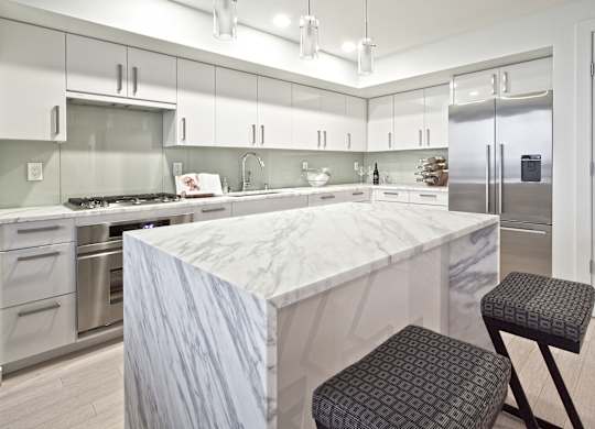 a large kitchen with a marble counter top and stainless steel appliances