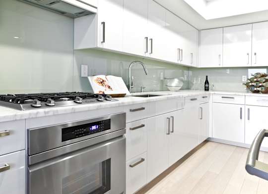 a white kitchen with stainless steel appliances and white cabinets