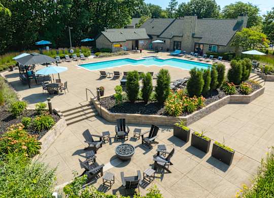 A large outdoor swimming pool surrounded by a patio with chairs and umbrellas.